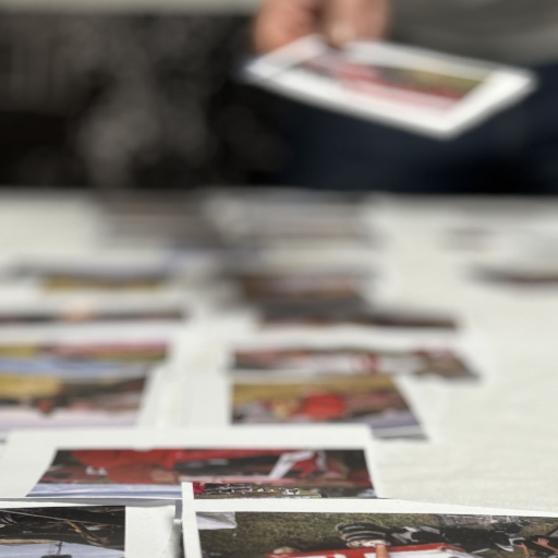 Hand adding a photo to a selection of images on a table